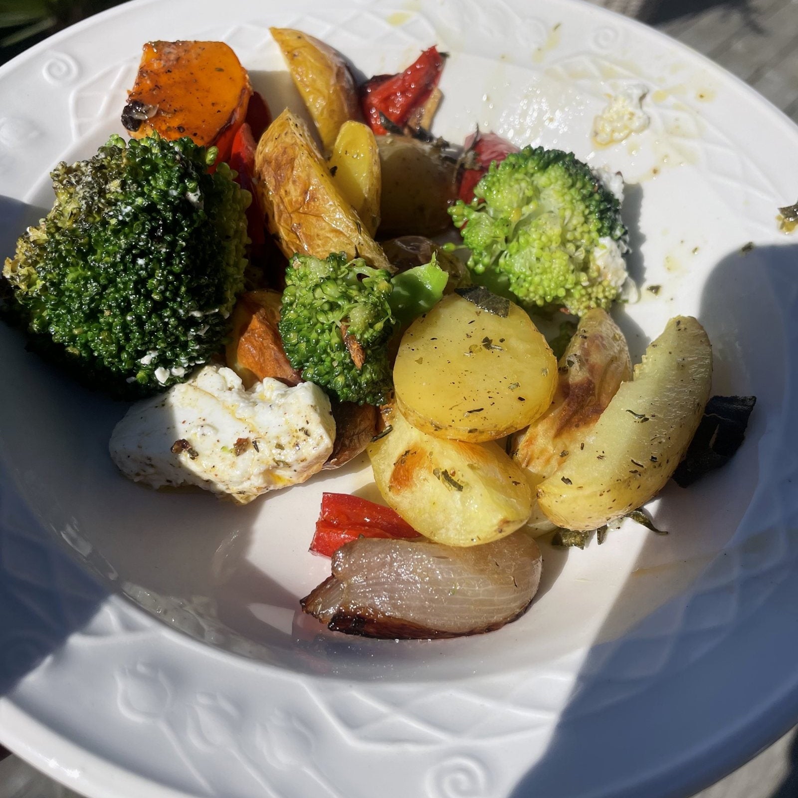 Ofenkartoffeln mit Rosmarin, Brokkoli, Kürbis, Paprika, Feta und roter Zwiebel auf einem weißen Teller