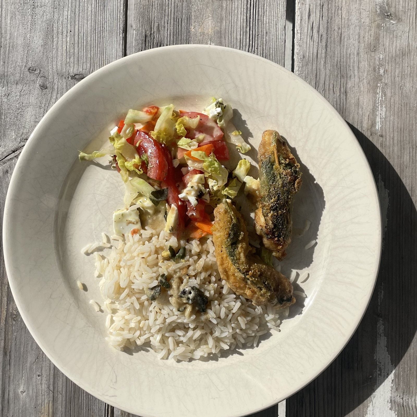 Hähnchen-Saltimbocca mit Salbei, Reis und Tomatensalat auf einem hellen Teller, von oben